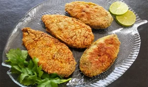 Goan style rava fried kingfish served with lemon wedges and basil leaves