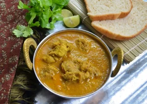 Goan style chicken xacuti served with sliced bread and a lemon wedge